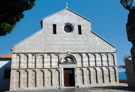 La chiesa della Beata Vergine Maria, un tempo cattedrale, presenta una facciata romanica in pietra rosa e bianca.