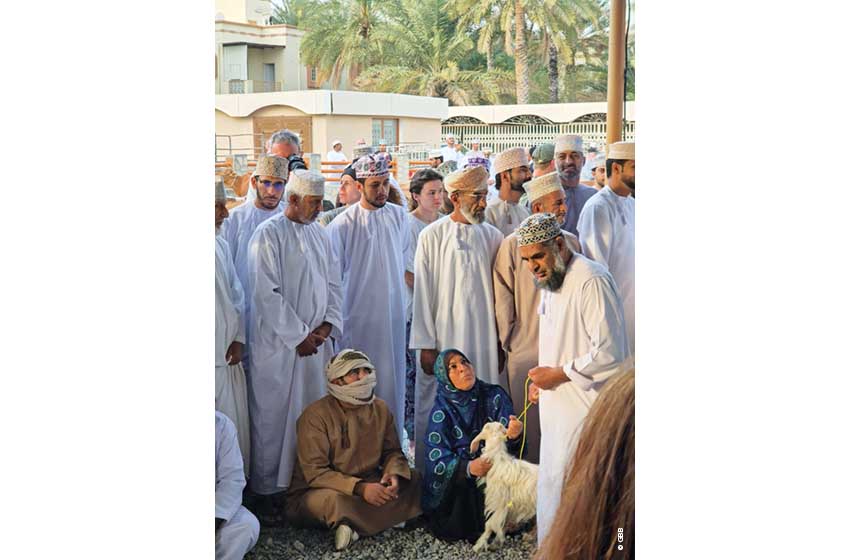 Oman-Nizwa-Fiera del Bestiame-capretta e venditori con donna