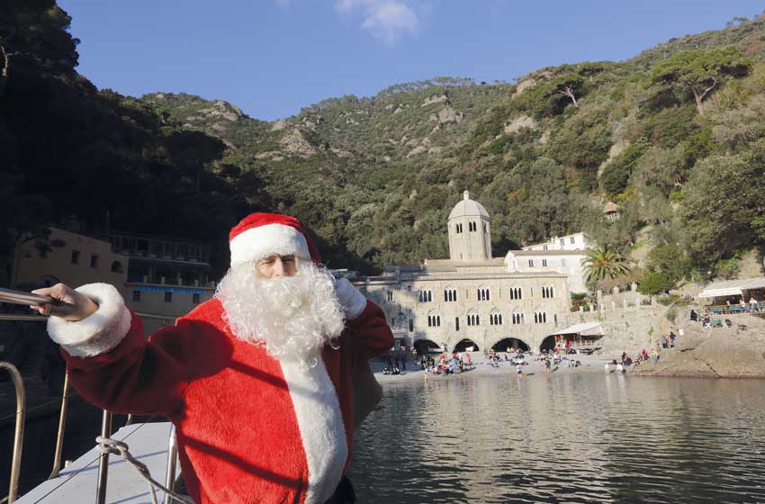 babbo natale in barca con edificio di camogli